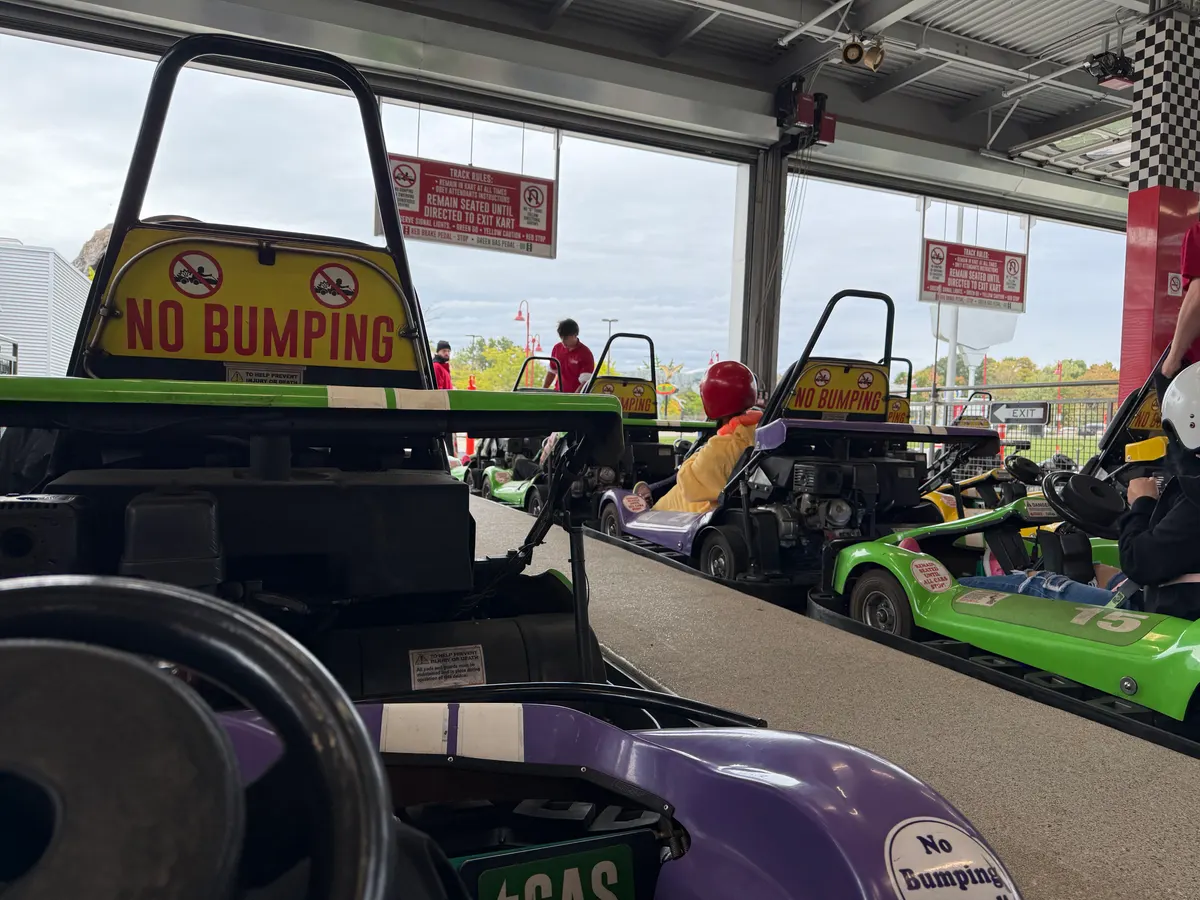 Go-karts lined up in a pit lane under “No bumping” signs.